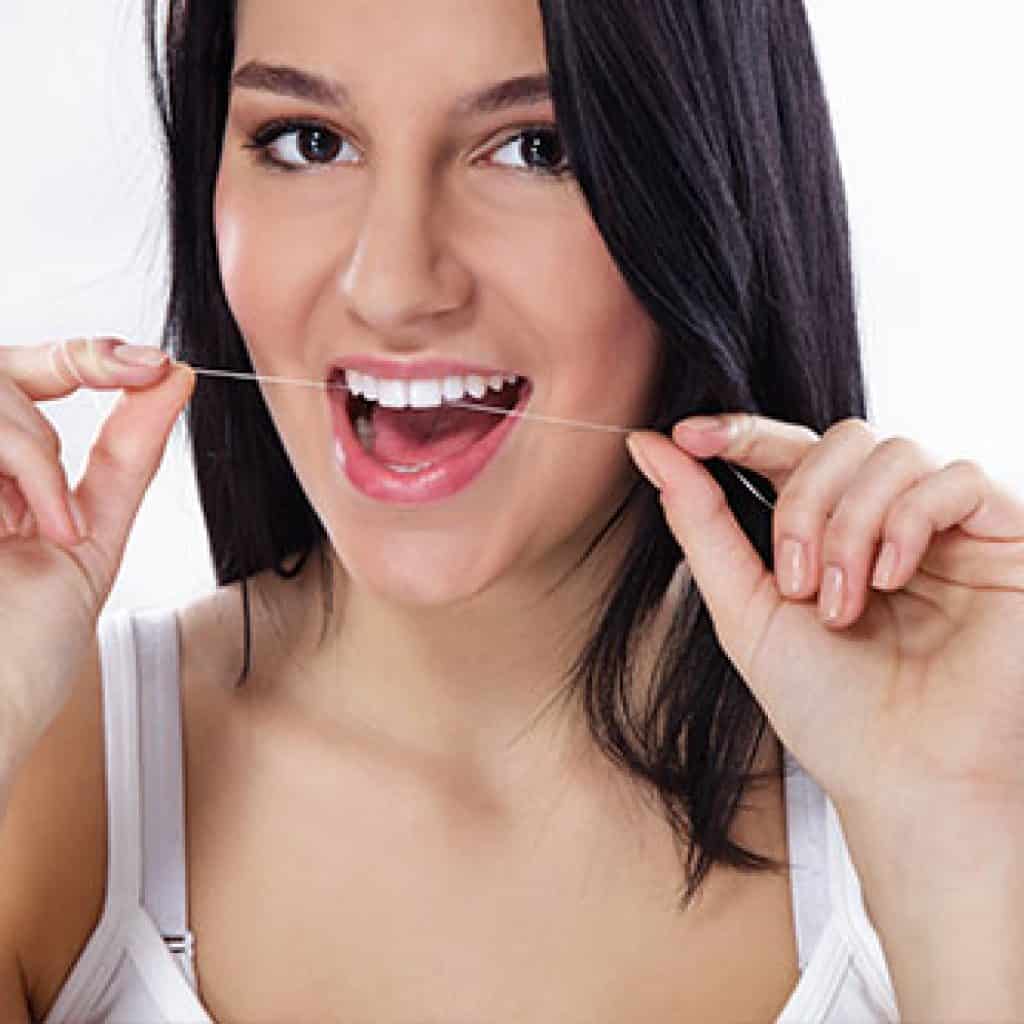 Lady Flossing Her Upper Front Teeth | Dental Prevention in West Liberty, IA, North Liberty, IA and Muscatine, IA | Gentle Family Dentists